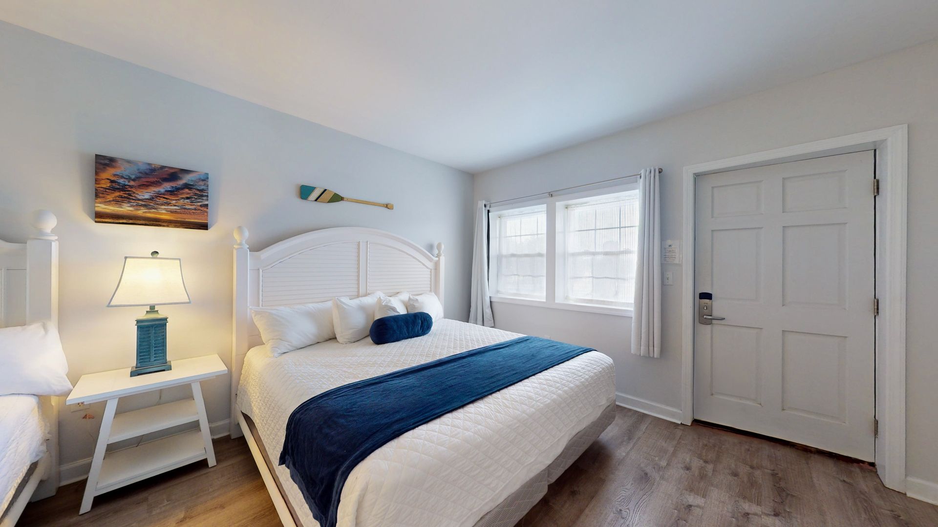 A bedroom with a bed , nightstand , lamp and window.