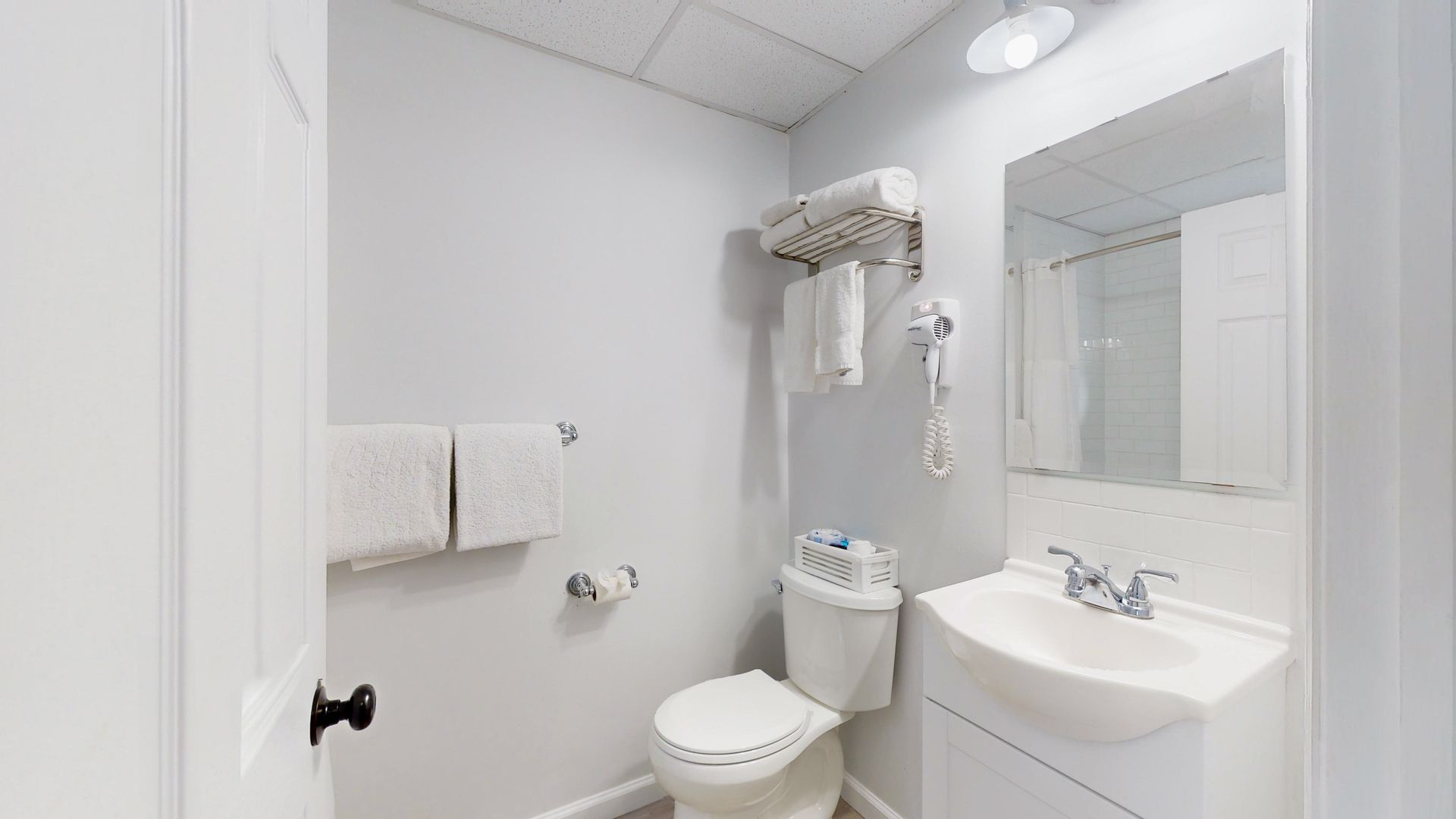 A bathroom with a toilet , sink and mirror.