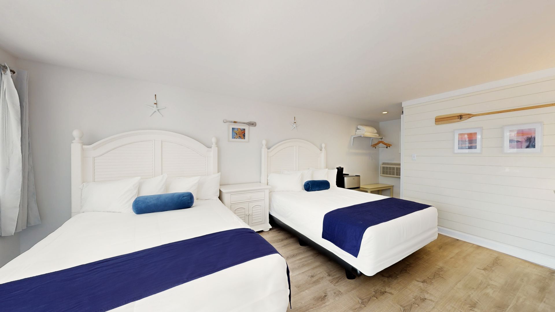 A hotel room with two beds and a blue blanket.