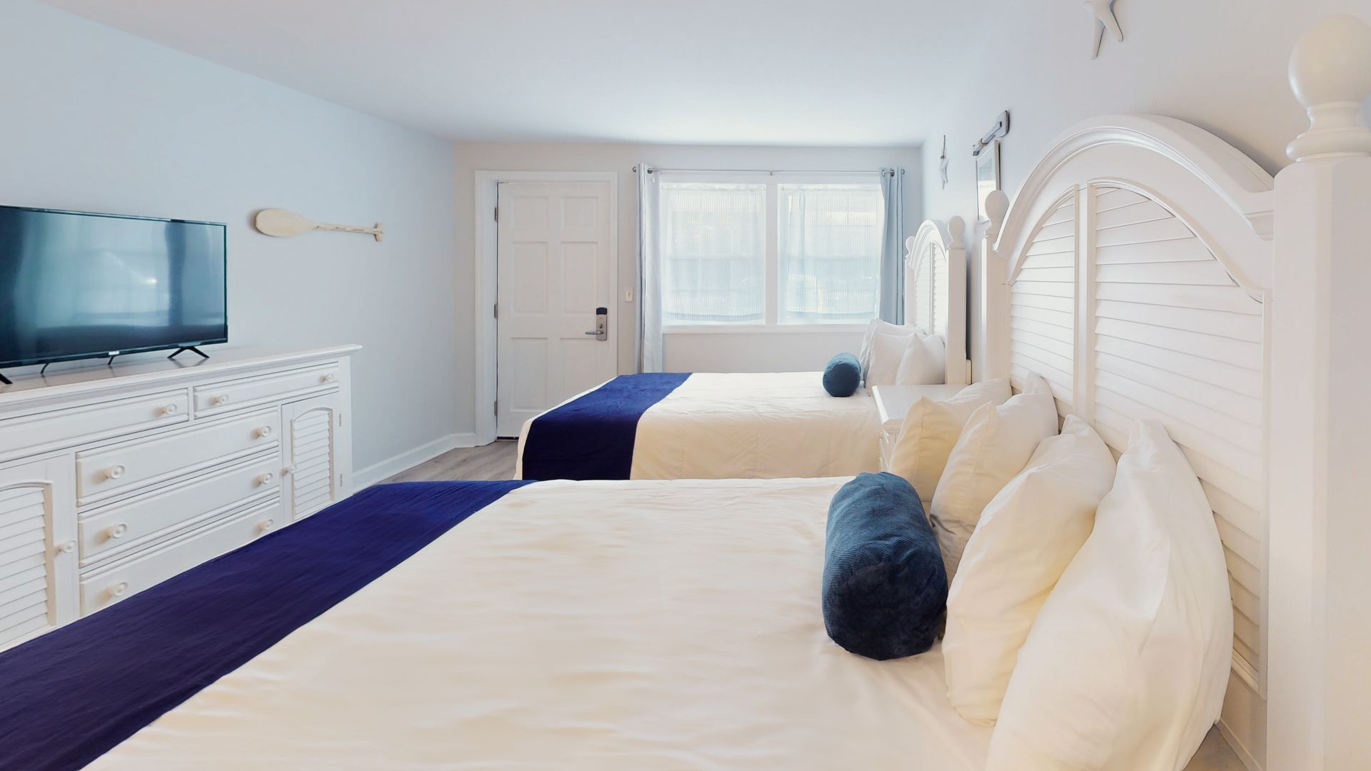 A hotel room with two beds and a flat screen tv.