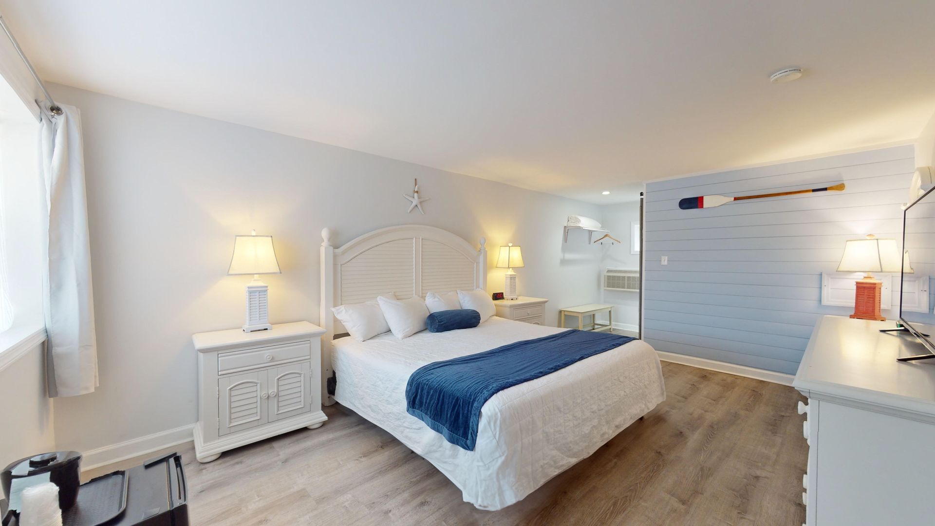 A hotel room with a king size bed , dresser , nightstand and television.