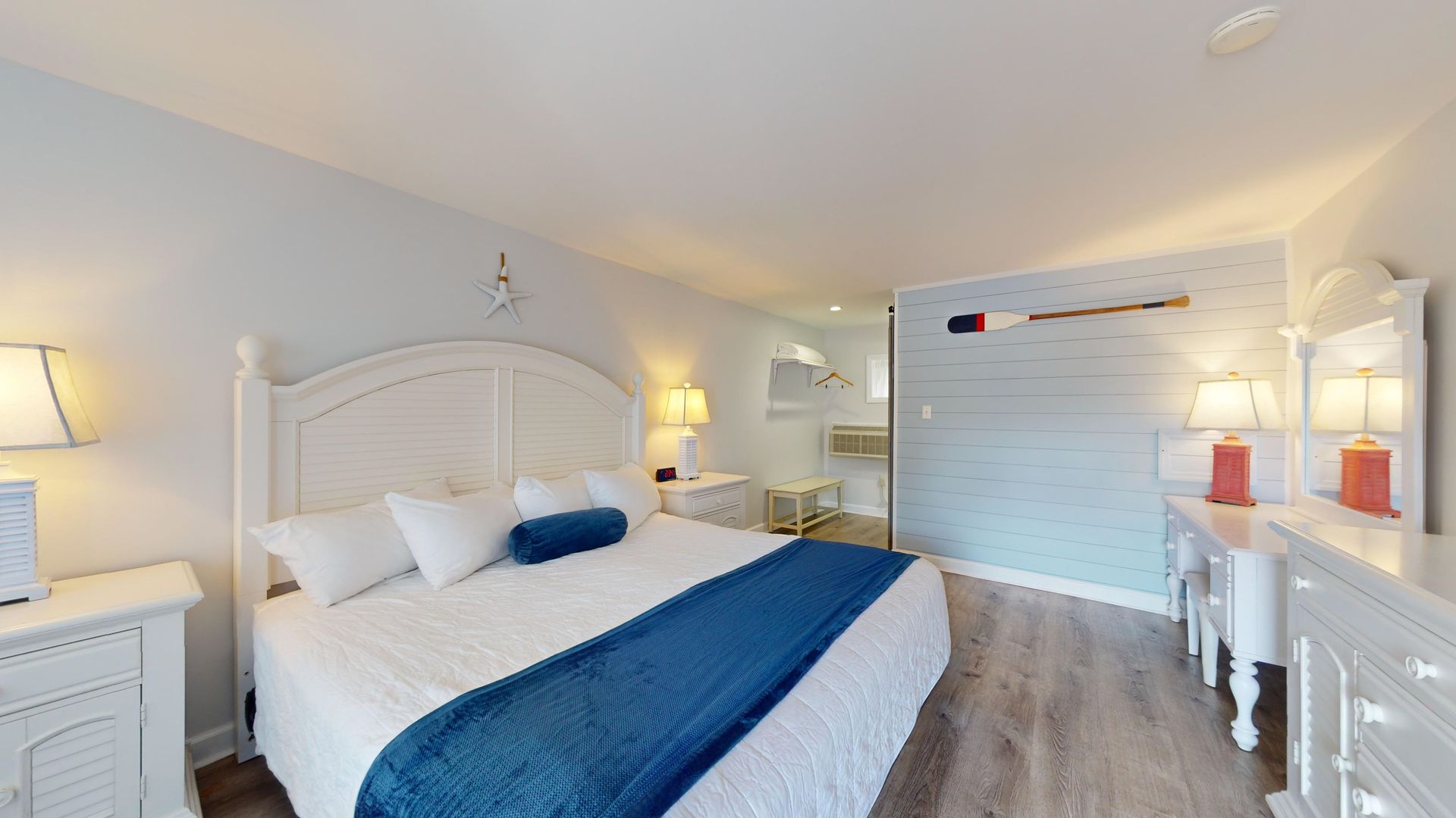 A bedroom with a king size bed , dresser , nightstand and mirror.