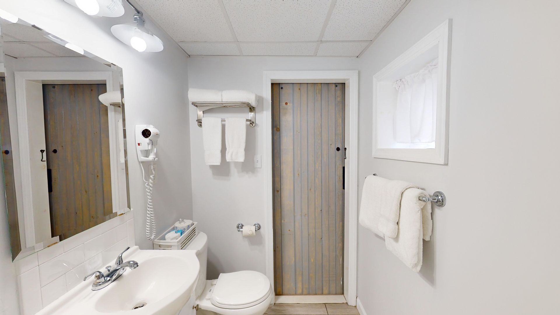 A bathroom with a sink , toilet , mirror and towels.