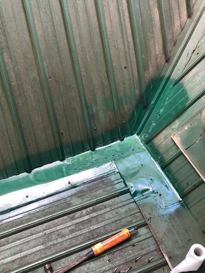 Green metal roof corner with sealant applied.