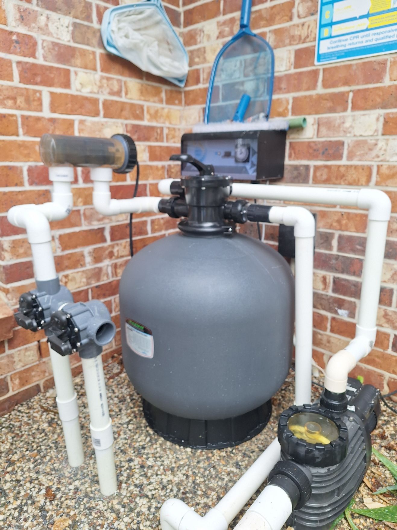A swimming pool filter is sitting next to a brick wall.