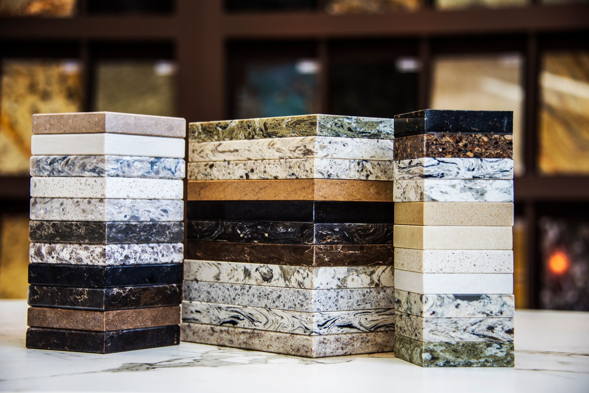 Stacks of granite countertop samples in various colors, displayed in a showroom setting.