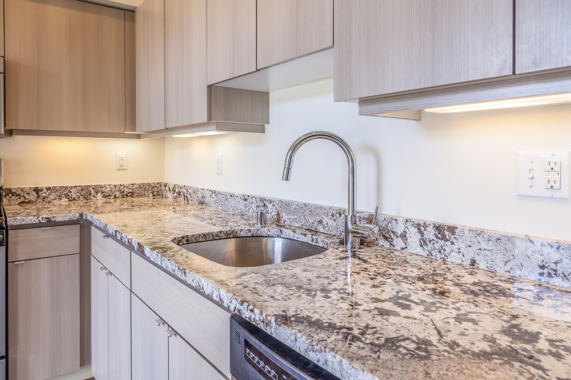 Kitchen with light-colored cabinets, granite countertop, stainless steel sink, and faucet.