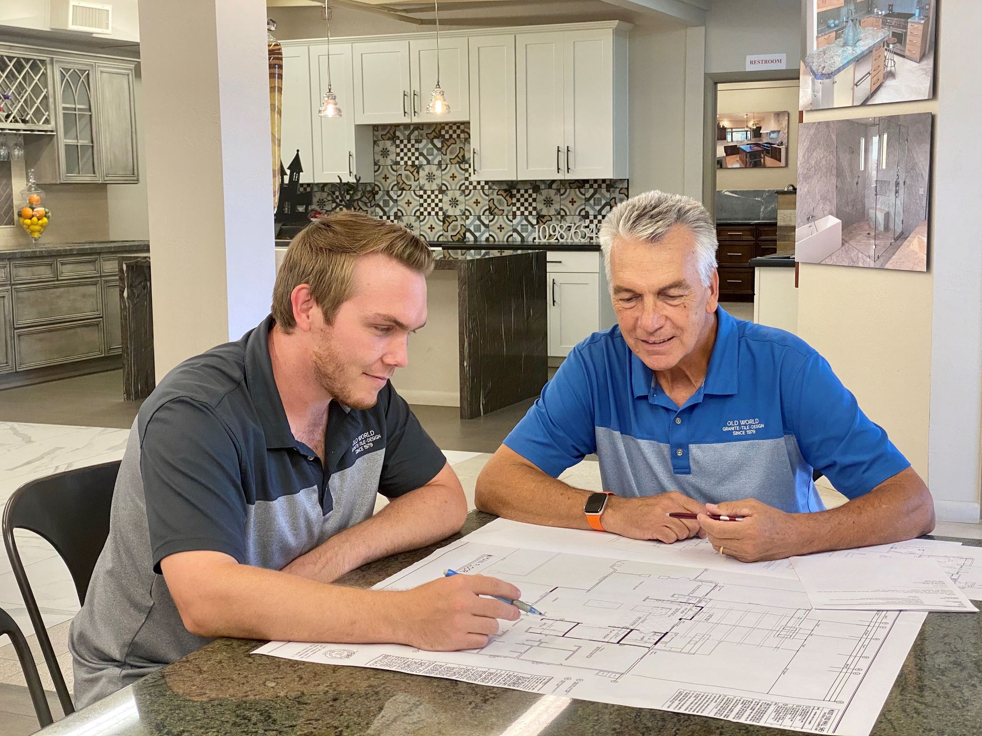 Cream-colored kitchen with granite island, cabinets, built-in appliances, and pendant lights.