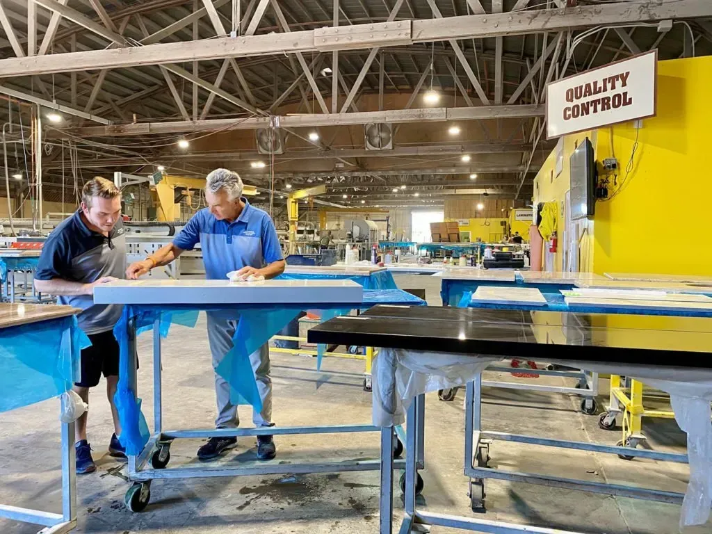 Two men inspecting countertops at a factory workstation, 