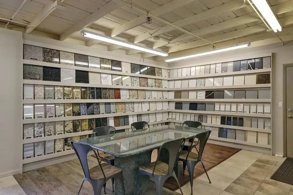 Room with shelves displaying stone samples, long table with chairs, and overhead lighting.