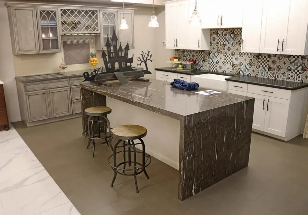 A kitchen with a dark-veined island countertop and white cabinetry. Two bar stools are placed at the island.