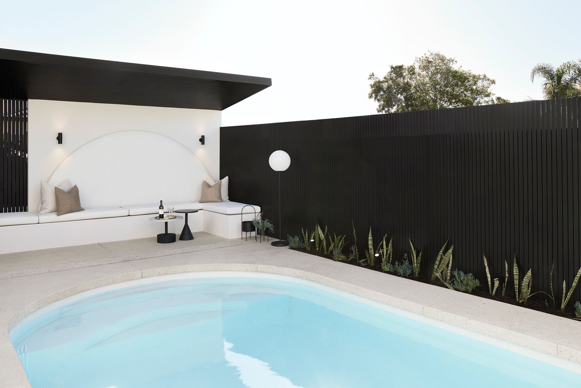 Pool area with white walls, black accents, and a pool with light blue water.