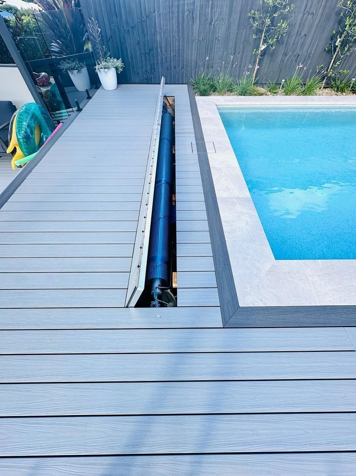 Poolside deck with a built-in cover storage area, next to a blue pool.