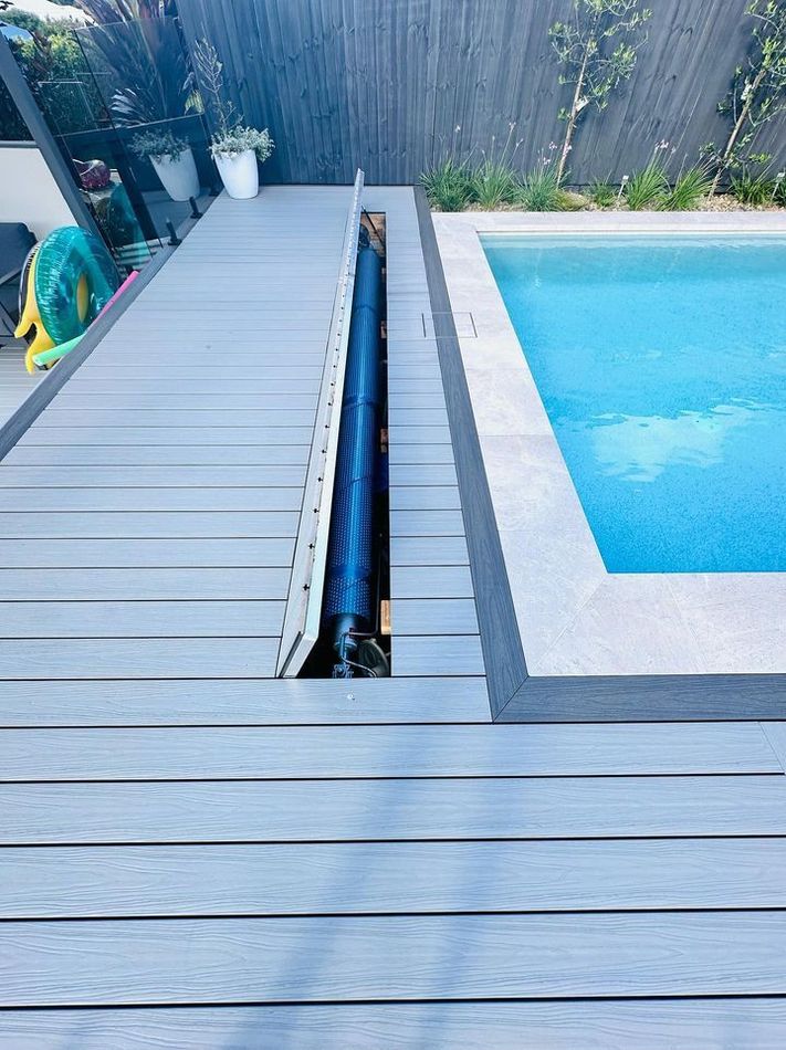 Poolside deck with a built-in cover storage area, next to a blue pool.