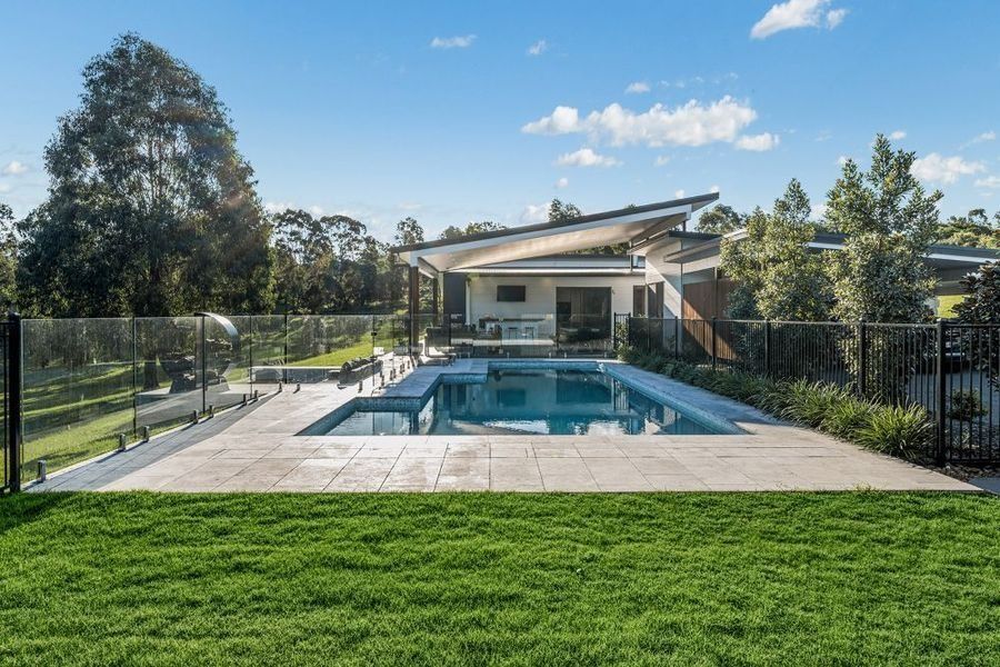 Swimming pool and spa in backyard of modern home, sunny day.