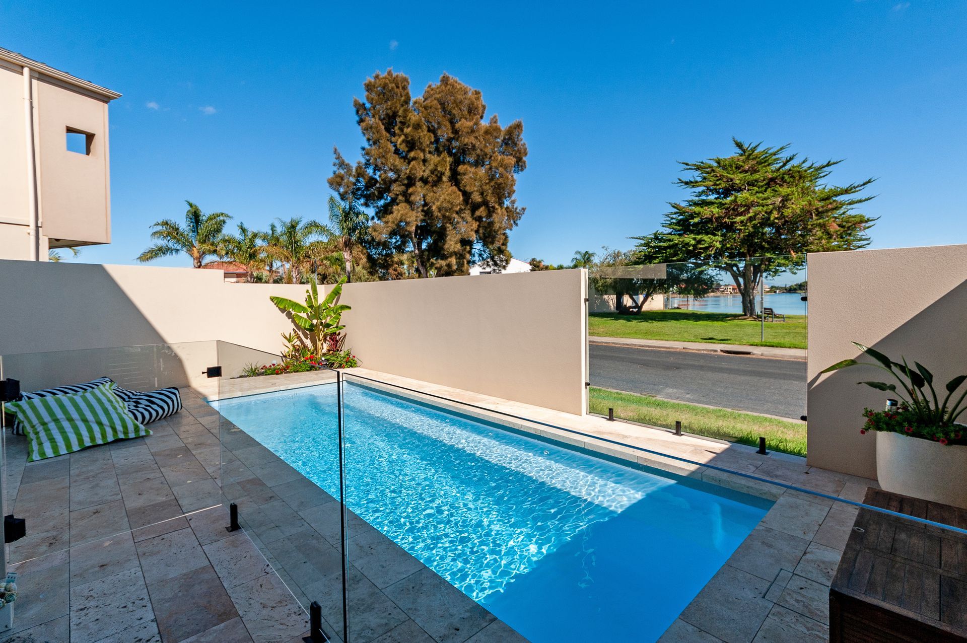 Pool with blue water, two lounge chairs, and an umbrella overlooking a landscape.