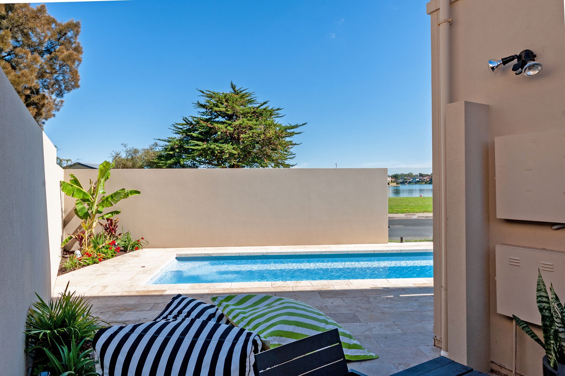 Pool with blue water and cover, glass fence, grass and ocean in background.