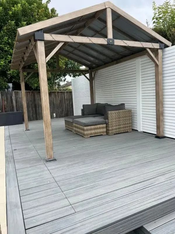 Gray composite deck with a wooden pergola sheltering outdoor seating.