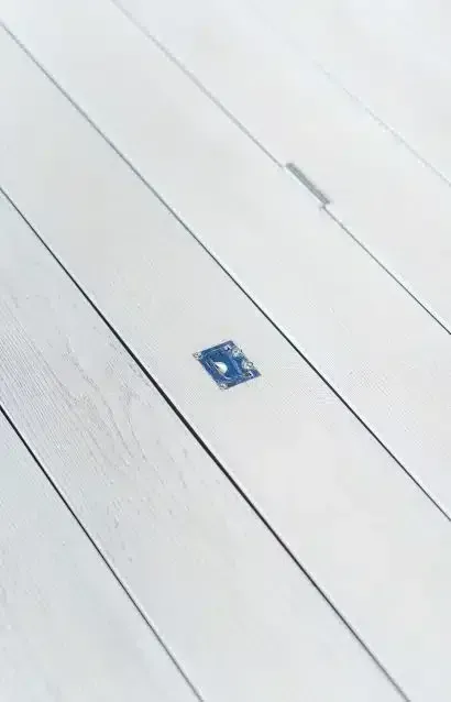 Small blue square object on a white wooden floor.