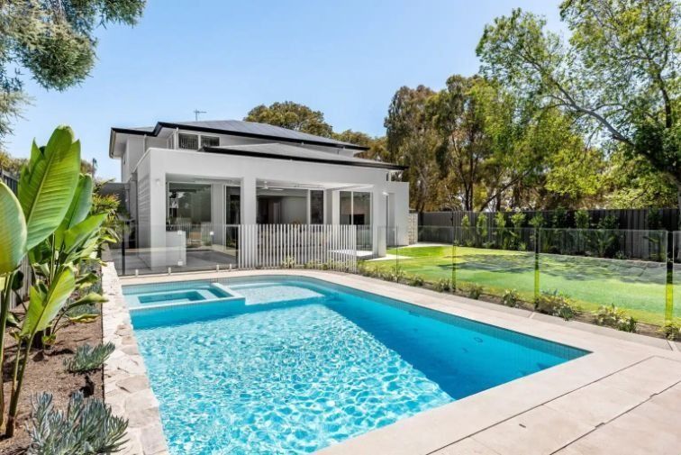A modern home with a pool and lush landscaping under a bright blue sky.