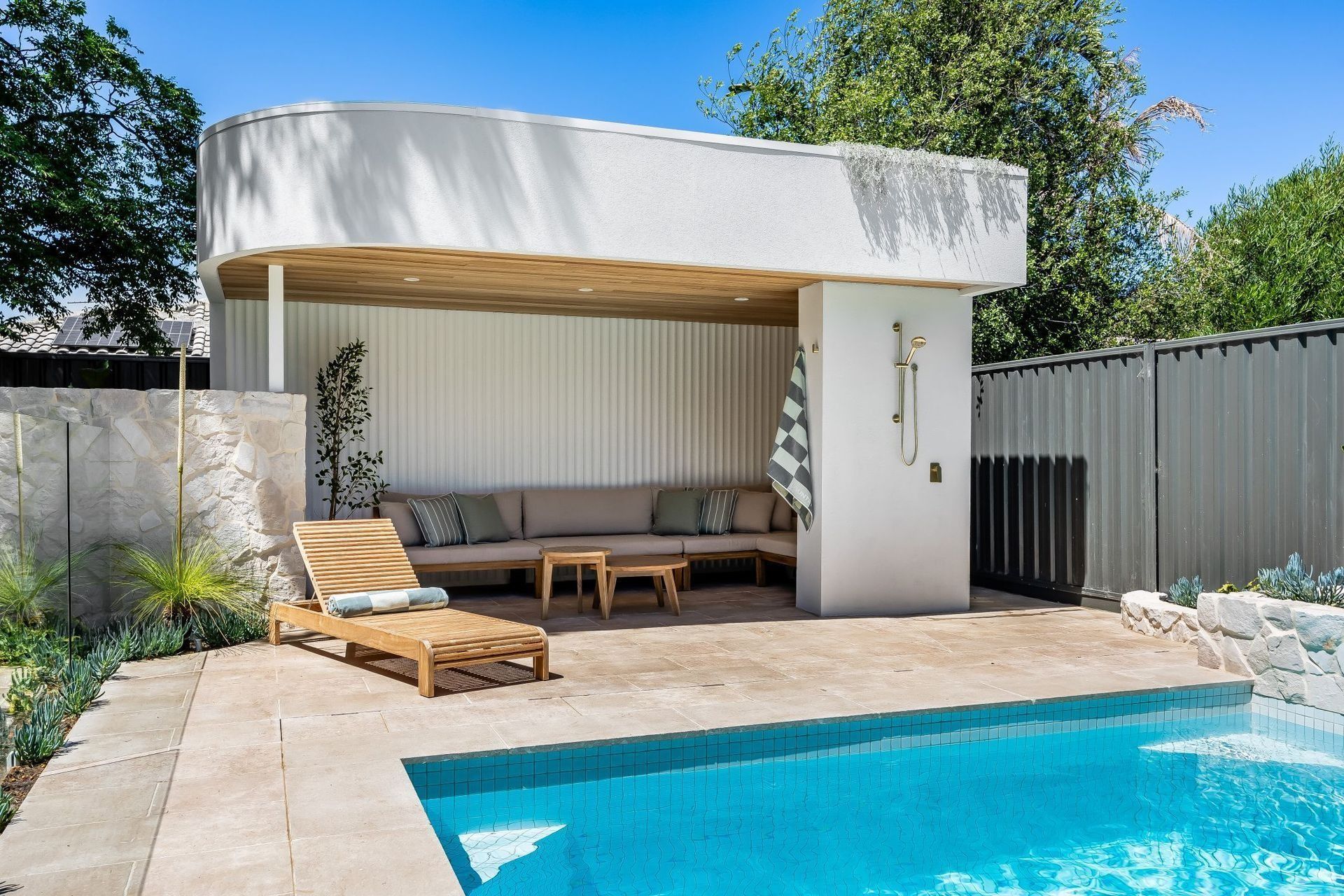 Poolside seating area with a pool, lounge chair, and a white cabana.