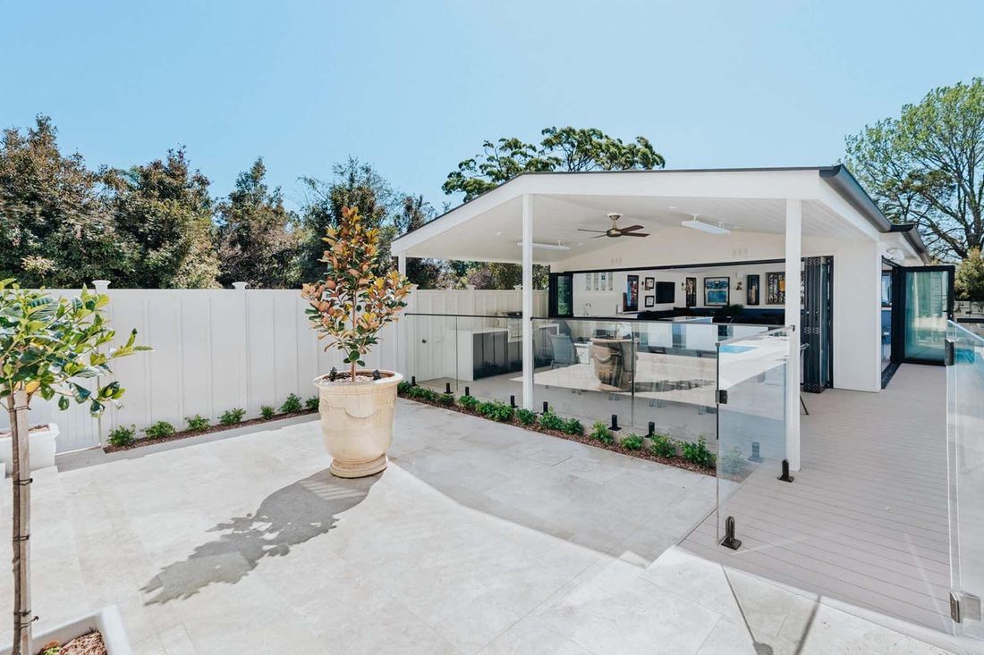 Outdoor patio with a white canopy, a glass railing, and a large potted plant.