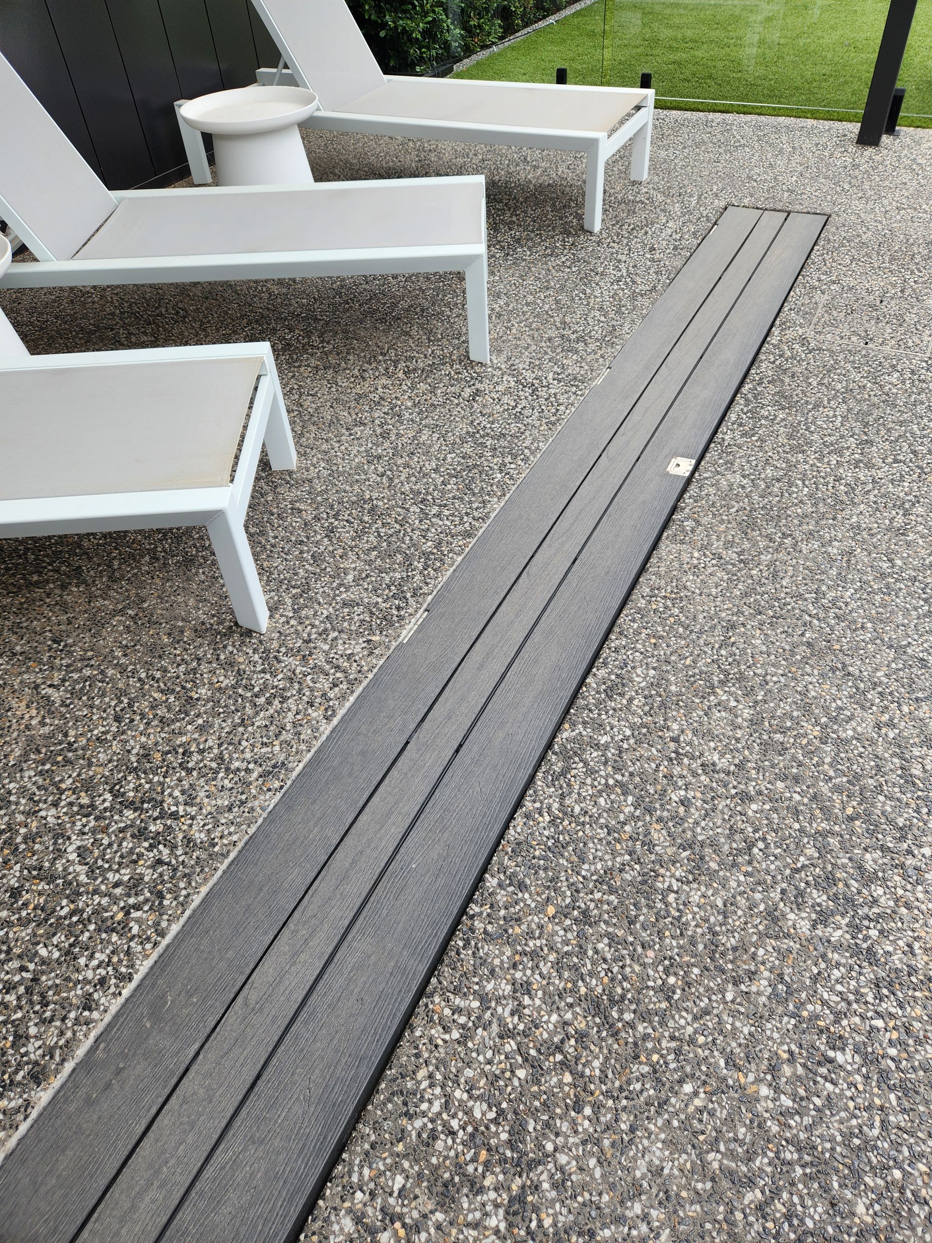 A pool cover roller mechanism installed in a stone patio. A blue cover is rolled up inside.