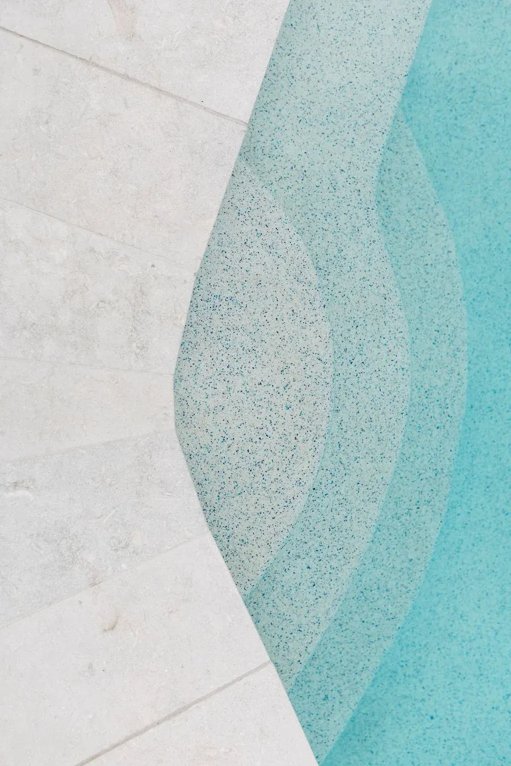 Pool edge with white stone and turquoise water.