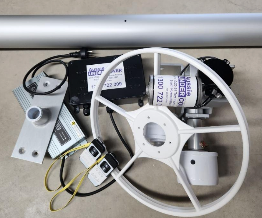 Rectangular blue swimming pool surrounded by stone tiles and a green hedge under a bright sky.