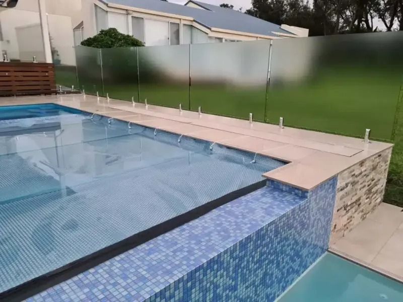 Pool with glass fencing, blue tile, and frosted glass privacy panels.