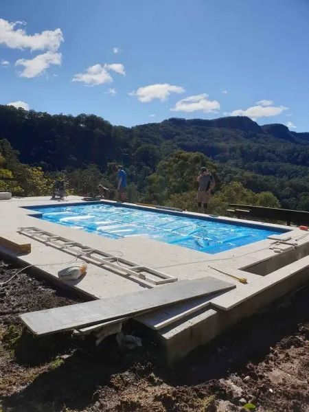 Pool under construction overlooking a mountainous landscape, blue tarp covers the pool.