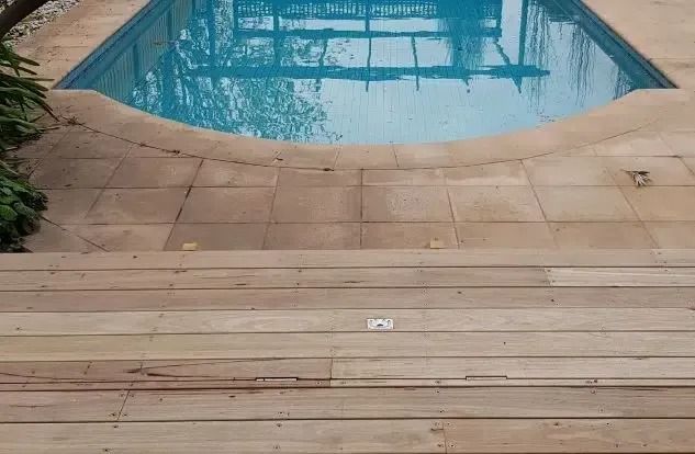 Wooden deck leading to a swimming pool with tan tiled border.