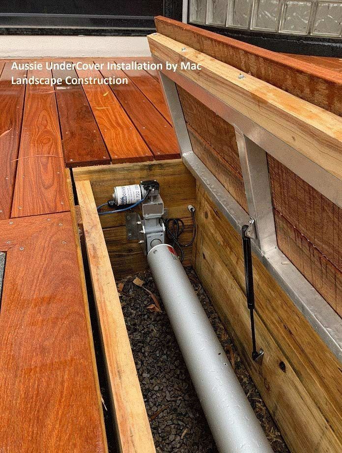 Under-cover deck installation: wooden deck with a built-in compartment. Silver cylinder and mechanics visible.