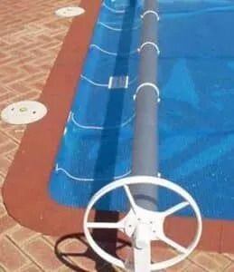 Pool cover rolled up, showing a blue cover over water, with a white winding mechanism.