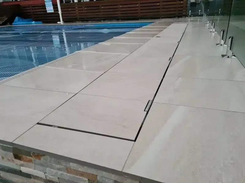 Poolside with beige tile and a section of covers over a pool feature.