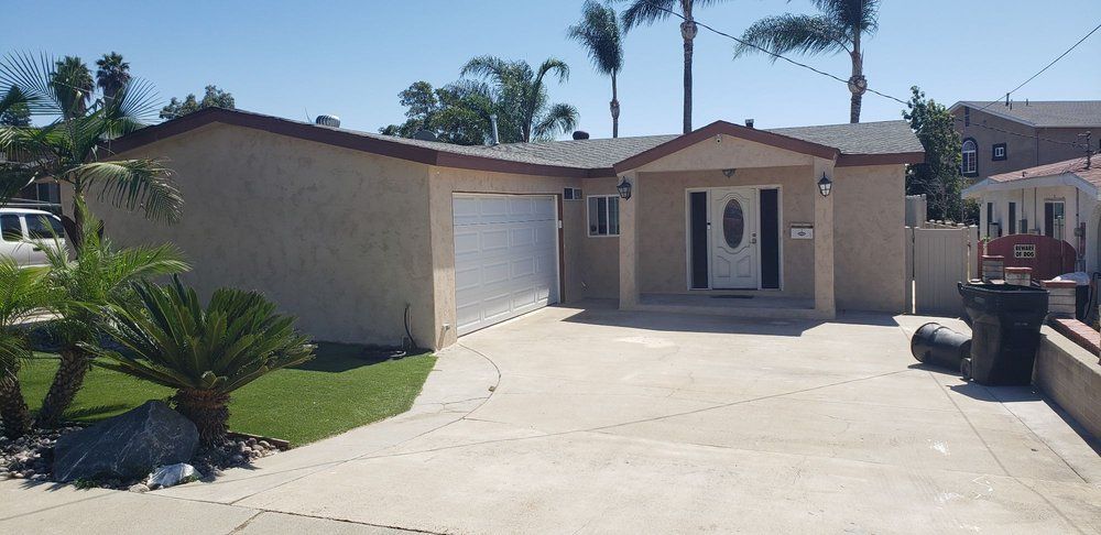 A house with a garage and palm trees in the background