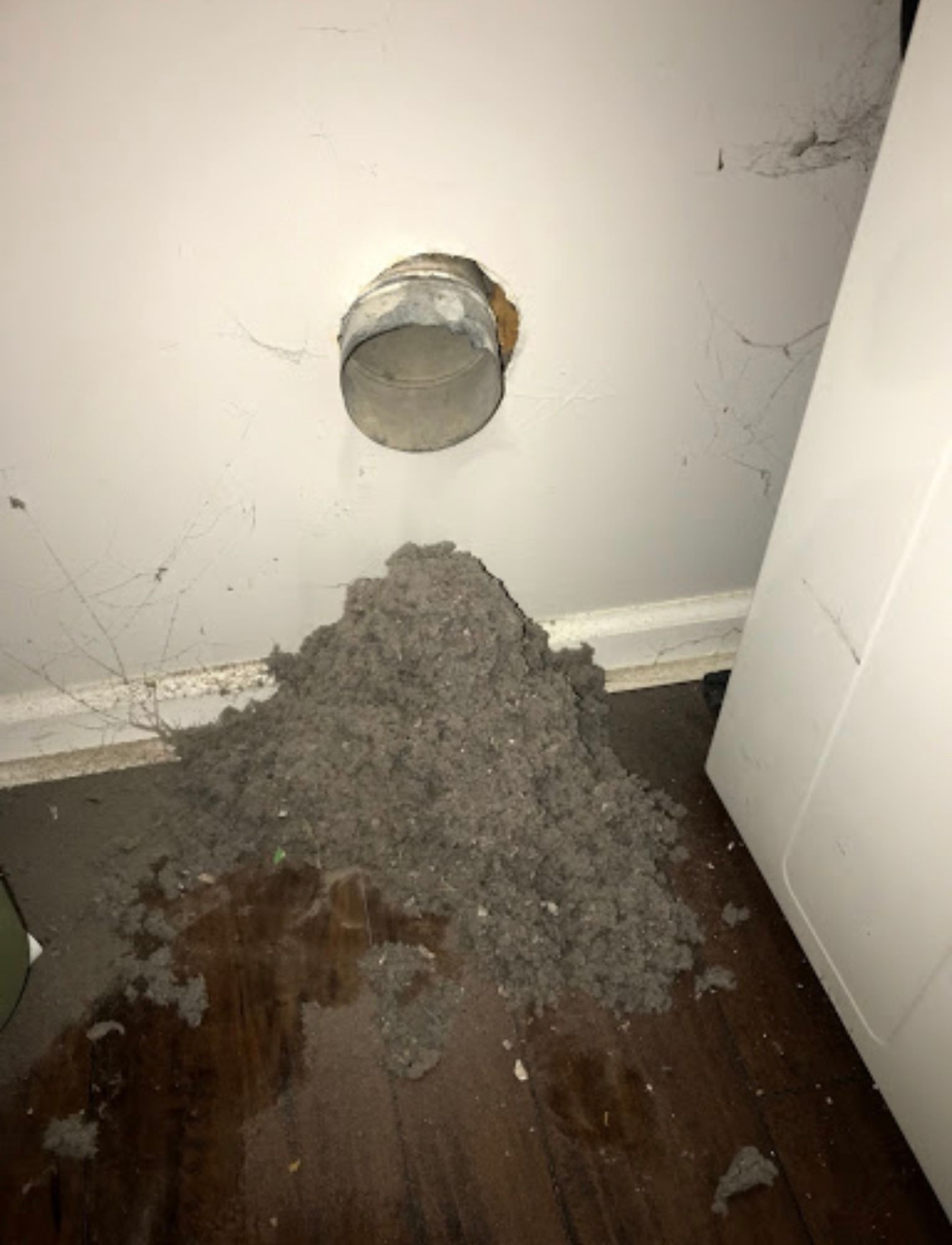 A hole in a wall with a bunch of dust coming out of it.