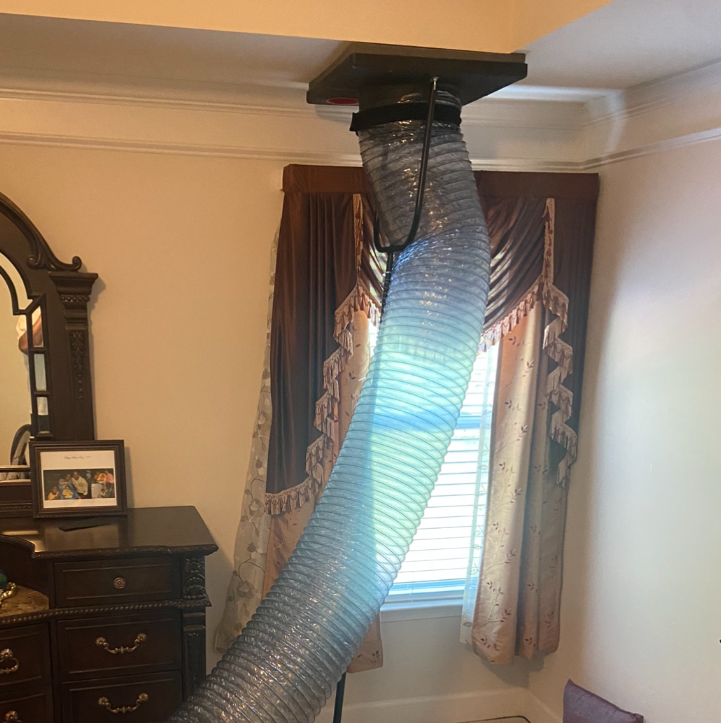 A large hose is hanging from the ceiling in a bedroom.