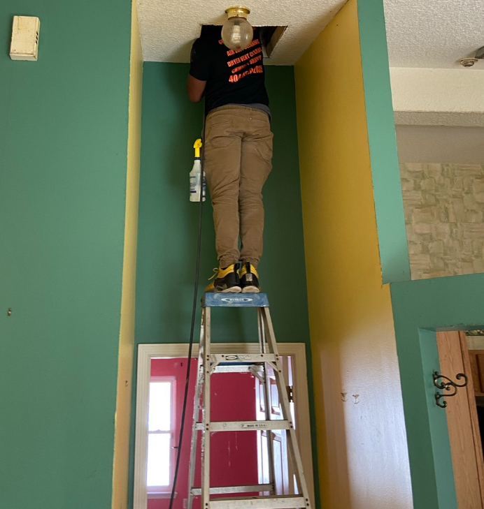 A man standing on a ladder with a shirt that says ' i love you ' on it