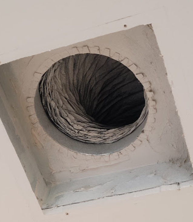 A hole in a wall with a hose coming out of it