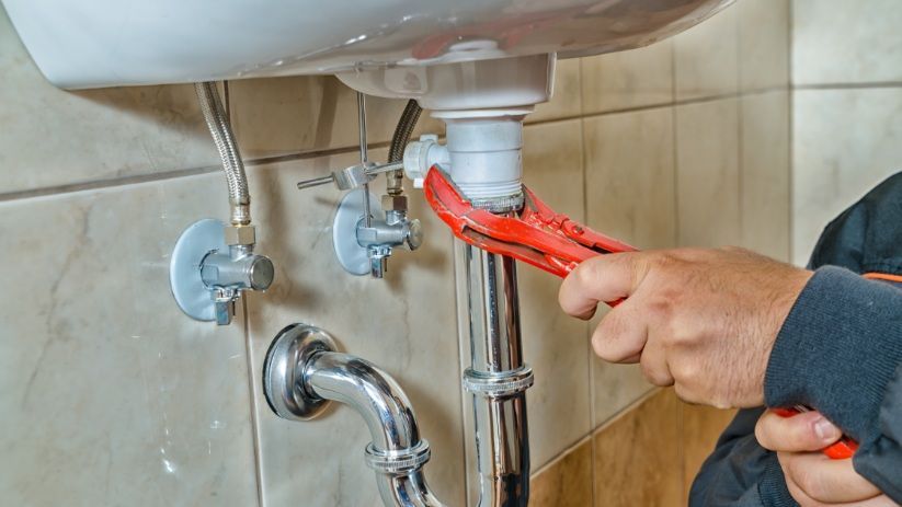 sole trader plumber tightening sink waste pipe