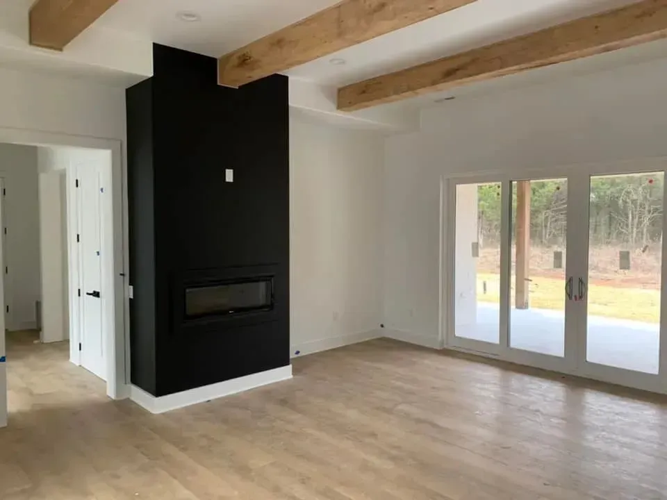 An empty living room with a fireplace and sliding glass doors.