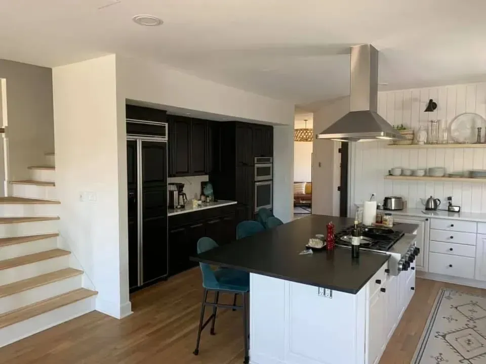A kitchen with a large island and stairs leading up to the second floor.