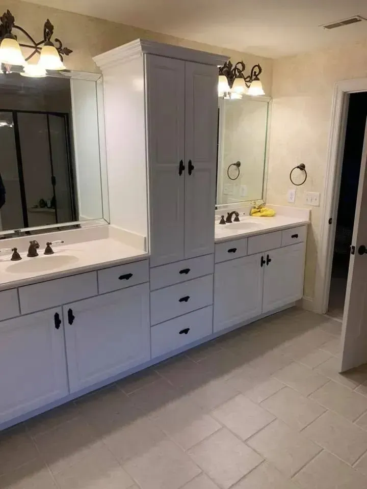 A bathroom with two sinks , two mirrors , and a large cabinet.