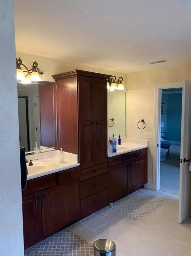 A bathroom with two sinks , a mirror and a trash can.