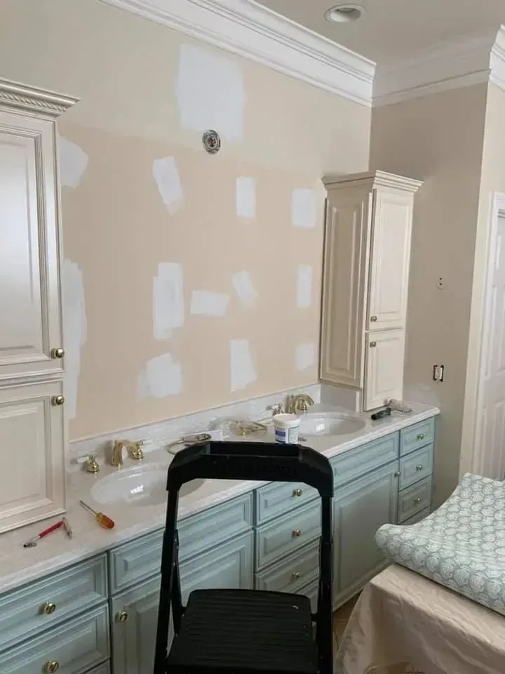 A bathroom with a sink , cabinets , and a chair.