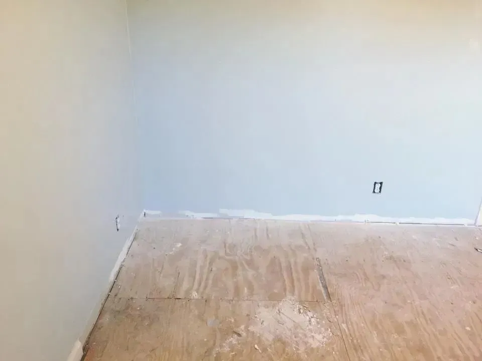 An empty room with a wooden floor and white walls.