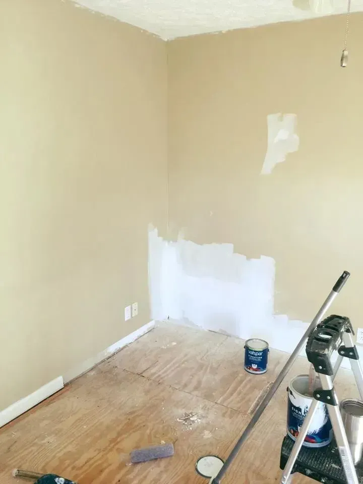 A room with a ladder and buckets of paint on the floor.