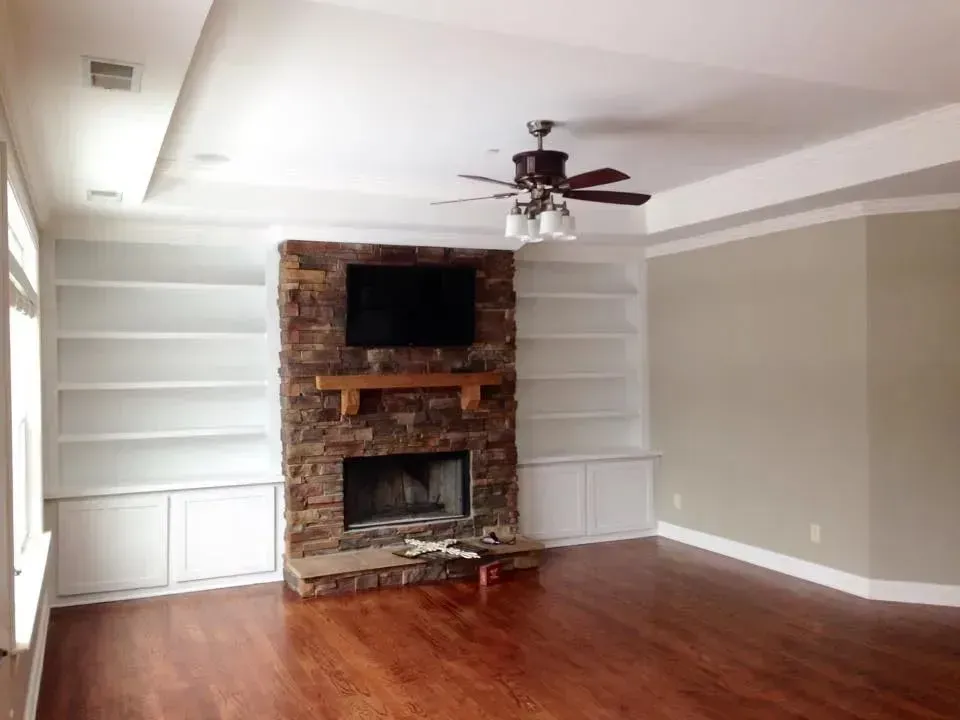 An empty living room with a fireplace and ceiling fan