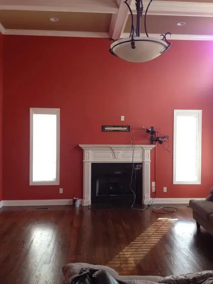 A living room with red walls and a fireplace